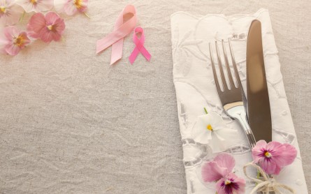 Pink ribbon table setting with pink flowers, copy space toning background