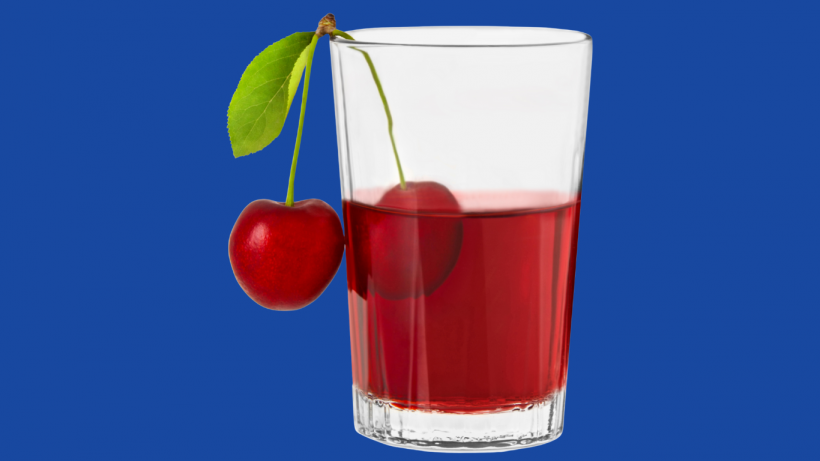 Cherry juice in a clear glass garnished with fresh cherries.