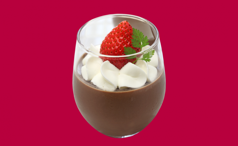 Chocolate mousse in a glass garnished with whipped cream and a strawberry.