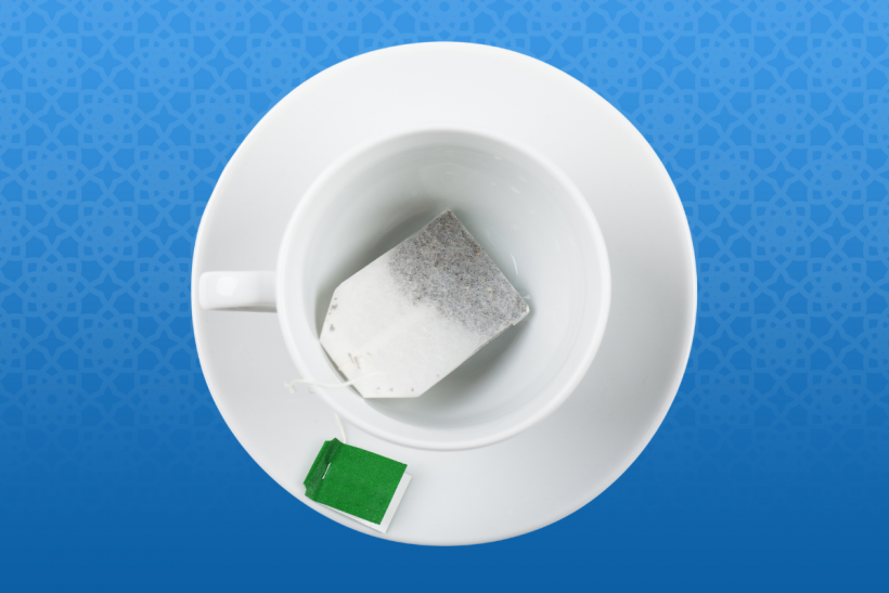 Tea bag in a white tea cup set on a white plate.