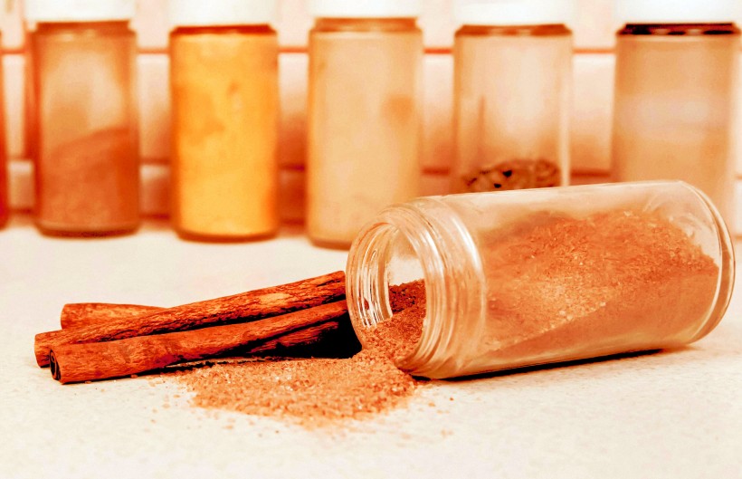 A jar of scattered cinnamon on a background of spices.